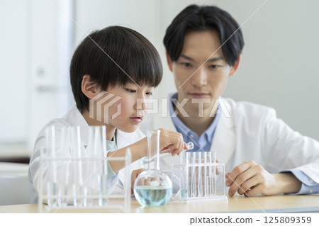 A fourth grade boy and his teacher conducting an experiment 125809359