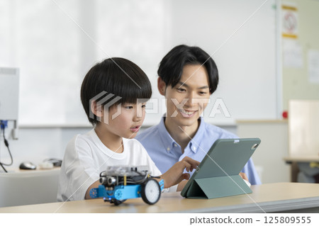 A fourth grade boy programming a robot. Image of a programming school for elementary school students. 125809555