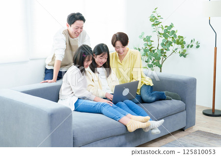 Families using personal computers in the living room 125810053