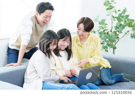 Families using personal computers in the living room 125810056