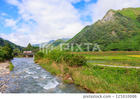 A diesel train on the Inbi Line crosses the Kamo River through a rustic landscape. A diesel train on the Inbi Line crosses the Kamo River through a rustic landscape. 125810086