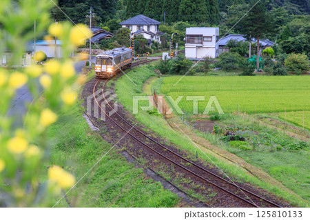 A diesel train on the Inbi Line quietly moves through a residential area. 125810133