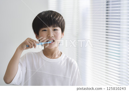 9 歲男孩刷牙，看著鏡頭 125810243
