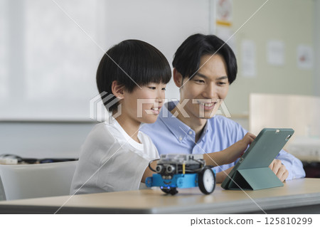 一名四年級男孩正在編寫機器人程式。針對小學生的程式設計學校的圖片。 125810299