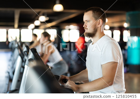 Young man exercising on exercise bike in gym 125810455