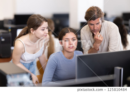 Man and two women discussing at computer Man and two women discussing at computer 125810484
