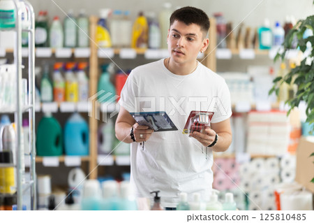Man carefully selects razor for shaving in the household goods department of supermarket Man carefully selects razor for shaving in the household goods department of supermarket 125810485