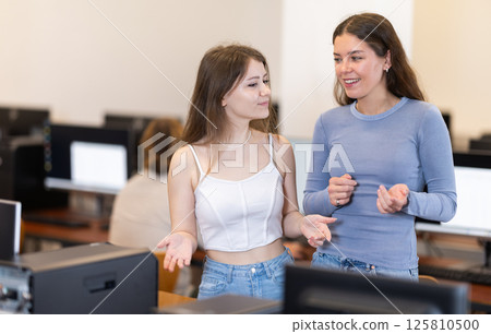 Female tutor and girl student speak near computer Female tutor and girl student speak near computer 125810500
