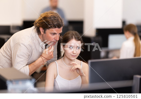 During computer lesson, male teacher helps girl student complete difficult task During computer lesson, male teacher helps girl student complete difficult task 125810501