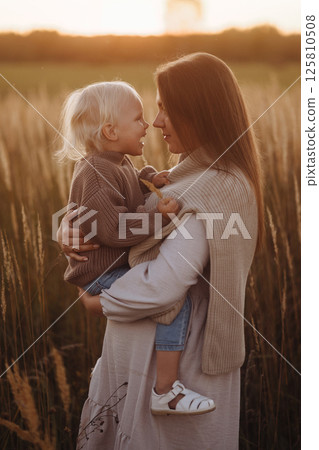 Side view Happy Mother and Child in Sunset Field Side view Happy Mother and Child in Sunset Field 125810508