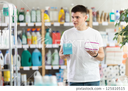 Young man chooses feminine pads in store 125810515