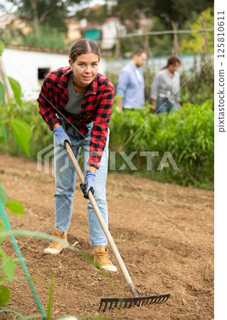 Peasant girl is working in garden with rake Peasant girl is working in garden with rake 125810611