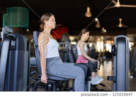 Young woman training her leg muscles on machine Young woman training her leg muscles on machine 125810647
