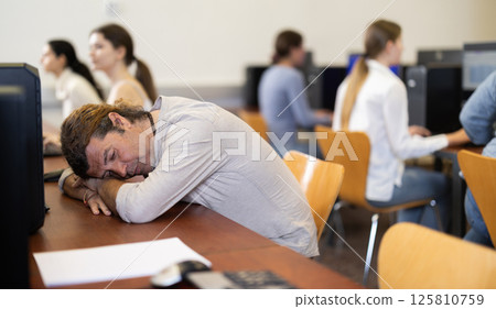 Adult man fell asleep at table in office Adult man fell asleep at table in office 125810759