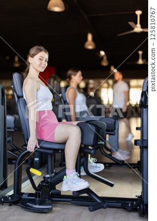 Young woman training her leg muscles on machine Young woman training her leg muscles on machine 125810767