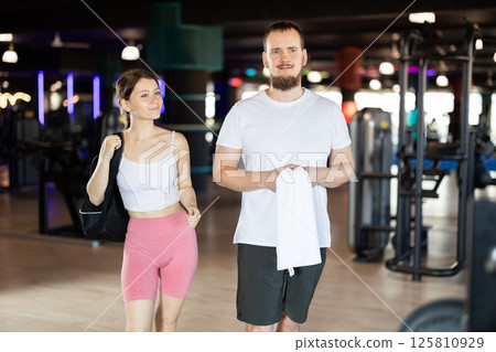 Young woman and man going to workout in gym Young woman and man going to workout in gym 125810929