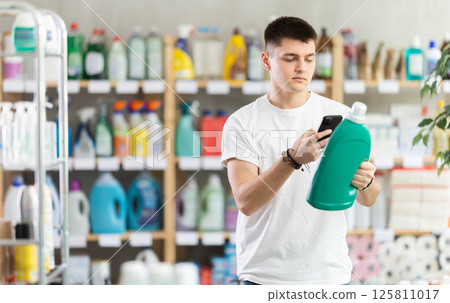 Young man scanning qr code for detergent Young man scanning qr code for detergent 125811017