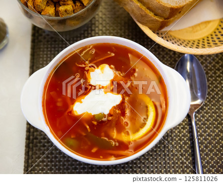Russian meat soup solyanka with assorted meat and sausages and vegetables Russian meat soup solyanka with assorted meat and sausages and vegetables 125811026