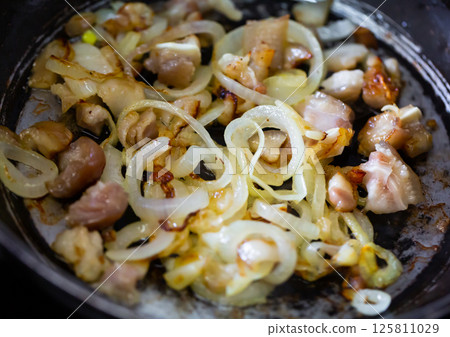 Cooking pork meat in pan with onions and spices 125811029