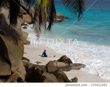 Handsome man sitting on stunning white sand beach 125812262