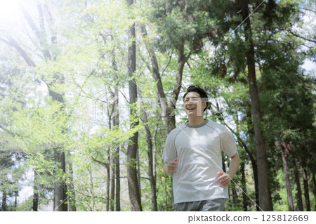 一名男子在林間道路上奔跑時仰望天空的上半身特寫 125812669