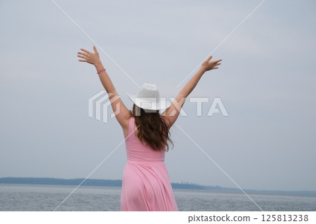 Joyful beach day Happy Woman with Raised Arms By the Sea. Joyful girl with outstretched arms up in the air celebrating nature Joyful beach day Happy Woman with Raised Arms By the Sea. Joyful girl with outstretched arms up in the air celebrating nature 125813238