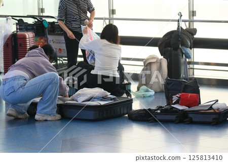 Foreign tourists packing their suitcases in the airport departure lobby 125813410