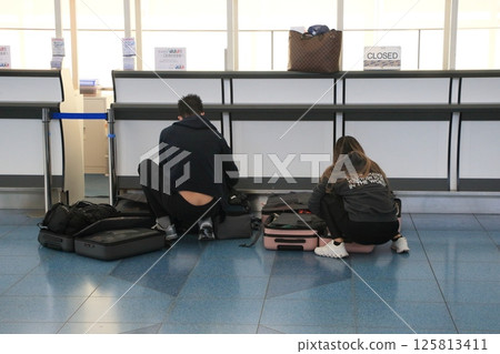 Foreign tourists packing their suitcases in the airport departure lobby 125813411