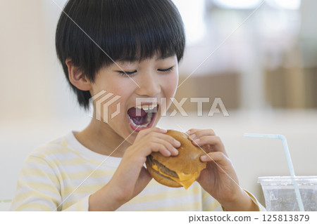 9 year old boy eating a hamburger 125813879
