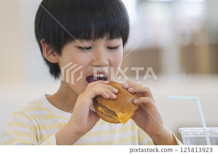 9 year old boy eating a hamburger 125813923