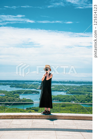 Image of a woman holding a camera under a blue sky Image of a woman holding a camera under a blue sky 125814123