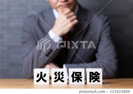 A middle-aged male businessman wearing a suit and a fire insurance block A middle-aged male businessman wearing a suit and a fire insurance block 125814809