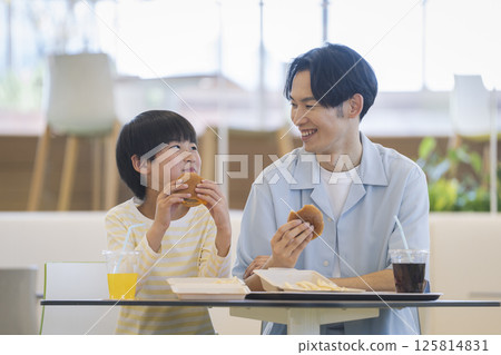 A 9-year-old boy and his father in his 30s eating at a food court A 9-year-old boy and his father in his 30s eating at a food court 125814831