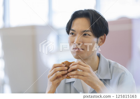 A man in his 30s eating a hamburger A man in his 30s eating a hamburger 125815163