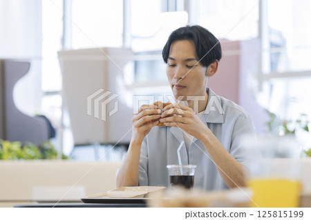 一名 30 多歲的男子正在吃漢堡包 一名 30 多歲的男子正在吃漢堡包 125815199