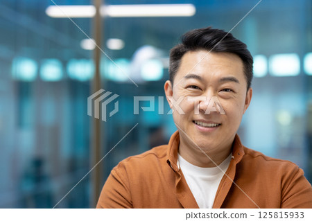 Smiling asian businessman in office exuding confidence and positivity. Casual attire enhances modern professional vibe, promoting workplace harmony and contemporary business culture. Smiling asian businessman in office exuding confidence and positivity. Casual attire enhances modern professional vibe, promoting workplace harmony and contemporary business culture. 125815933