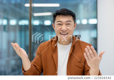 Webcam view, successful Asian man looking at camera smiling and communicating with colleagues and partners. Online business meeting, conference presentation, businessman sitting inside office Webcam view, successful Asian man looking at camera smiling and communicating with colleagues and partners. Online business meeting, conference presentation, businessman sitting inside office 125816142