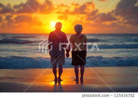 Elderly couple standing barefoot on a sandy beach, enjoying the serene sea at sunset. Senior couple holding hands on a beach, their bare feet touching the sand as the sun sets over the horizon Elderly couple standing barefoot on a sandy beach, enjoying the serene sea at sunset. Senior couple holding hands on a beach, their bare feet touching the sand as the sun sets over the horizon 125816782