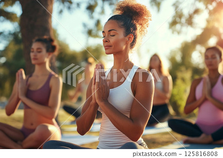 Happy women practicing yoga in a summer outdoor setting, celebrating wellness, fitness, and a positive lifestyle. A fit group of women practicing yoga outside on a sunny summer day 125816808