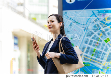 一位女商務人士透過查看地圖和智慧型手機來檢查位置 125817314