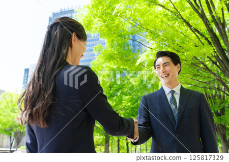 Business people shaking hands in a city with fresh greenery 125817329