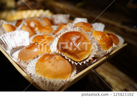 Freshly baked round buns in a basket on a wooden table. 125821102
