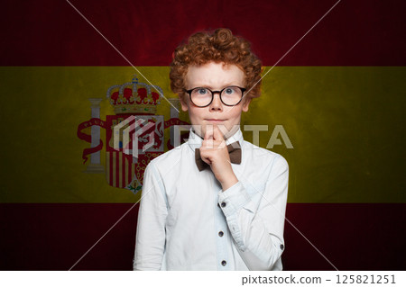 Thinking child boy in school uniform on Spanish flag background. Education and childhood in Spain Thinking child boy in school uniform on Spanish flag background. Education and childhood in Spain 125821251