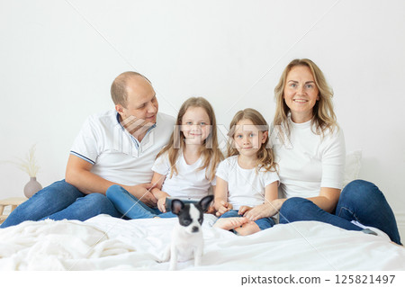 Lovely parents and their daughter having fun on a bed indoors 125821497