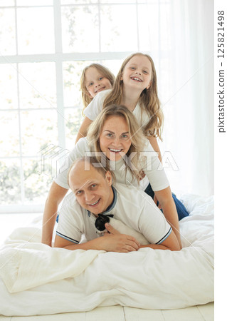 Happy parents and their daughter having fun on a bed indoors 125821498