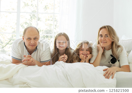 Portrait of parents and their daughter having fun on a bed indoors Portrait of parents and their daughter having fun on a bed indoors 125821500