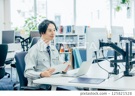 A young man in work clothes working at a company 125821528