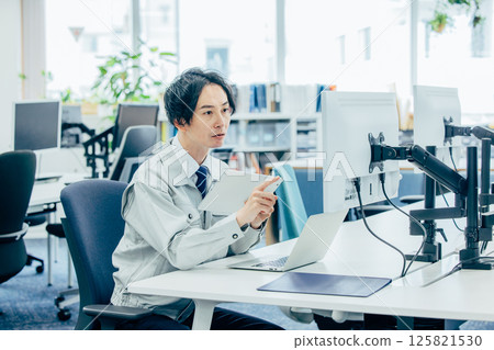 A young man in work clothes working at a company A young man in work clothes working at a company 125821530