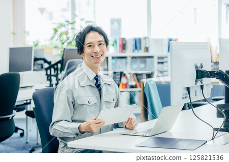 A young man in work clothes working at a company 125821536