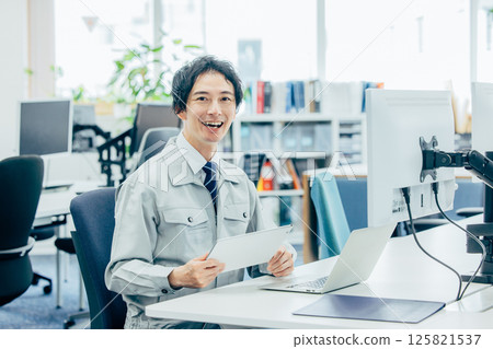 A young man in work clothes working at a company A young man in work clothes working at a company 125821537